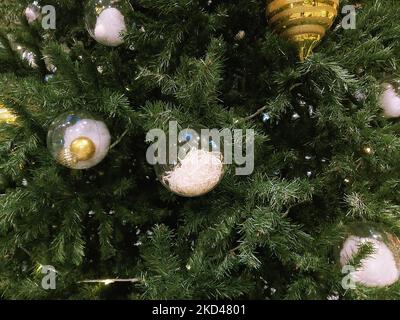 Am Vorabend der Feiertage hängen verschiedene Neujahrsspielzeuge an einem grünen Weihnachtsbaum. Stockfoto