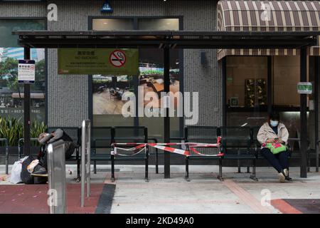 Hongkong, China, 5. März 2022, Eine Frau und ein obdachloser Mann sitzen auf einer Bank auf einem öffentlichen Platz in der Nähe von Yaumatei, mit mehreren anderen Bänken, die zu sozialen Distanzierungszwecken aufgeklebt wurden. (Foto von Marc Fernandes/NurPhoto) Stockfoto