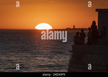 Beim Sonnenuntergang am Ufer des Flusses Tejo in Lissabon werden Silhouetten von Menschen gesehen. 28. Februar 2022. Besucher versammeln sich um den Belem-Turm, um den Sonnenuntergang vor dem Ende des Winters zu erleben. (Foto von Jorge Mantilla/NurPhoto) Stockfoto