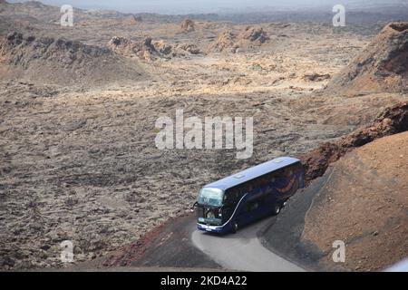 Ein horizontales Bild eines Touristenbusses, der auf einer schmalen Straße durch die vulkanische Landschaft fährt Stockfoto