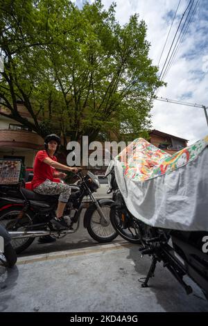 Medellin, Antioquia, Kolumbien - Juni 2 2022: Junger Mann auf einem Motorrad in der Straße durch einen großen Baum starrt verwirrt Stockfoto