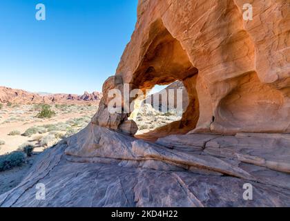 Nahaufnahme durch uralte Felsformationen im Valley of Fire mit Canyon im Hintergrund. Stockfoto