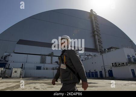 (ANMERKUNG DES HERAUSGEBERS:DATEI-FOTO) Ein Arbeiter geht am 26. April 2019 vor einem neuen Schutzhaus über die Reaktoreinheit 4 im Kernkraftwerk Tschernobyl in der Region Kiew, Ukraine. - Das Kernkraftwerk Tschernobyl übermittelt keine Daten mehr an die Atomwache der Vereinten Nationen, teilte die Agentur am Dienstag mit, da sie Besorgnis über die Mitarbeiter äußerte, die unter russischer Aufsicht in der ukrainischen Anlage arbeiten. Stockfoto