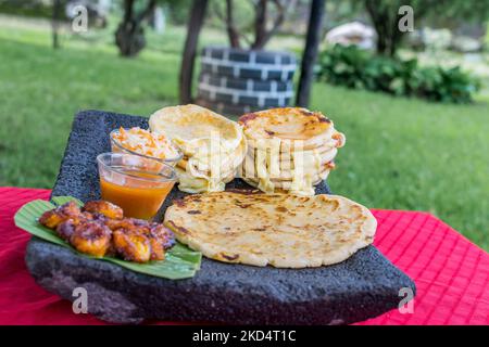 Typisch salvadorianisches Gericht, Käse-Pupusas mit Kohl und Tomatensauce. Reis- und Maispupusas gefüllt mit Käse, Bohnen oder anderen Zutaten Stockfoto