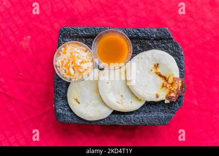 Typisch salvadorianisches Gericht, Käse-Pupusas mit Kohl und Tomatensauce. Reis- und Maispupusas gefüllt mit Käse, Bohnen oder anderen Zutaten Stockfoto