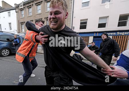 Jedburgh, Donnerstag, 10. März 2022. Ein Mann ist in Angriff genommen, während er trägt die â € œBaâ € während der jährlichen "Fastern Eve Handba" Veranstaltung in Jedburgh High Street in den Scottish Borders am 10. März 2022 in Jedburgh, Schottland. Die jährliche Veranstaltung, die im 18. Jahrhundert begann, findet heute statt und umfasst zwei Teams, die Uppies (Bewohner aus dem oberen Teil von Jedburgh) und die Doonies (Bewohner aus dem unteren Teil von Jedburgh), die den Ball entweder auf den oberen oder unteren Rand der Stadt bringen. Der Ball, der aus Leder besteht, mit Stroh gefüllt und mit Bändern verziert ist, wird in die Menge geworfen, um die zu beginnen Stockfoto