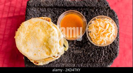 Typisch salvadorianisches Gericht, Käse-Pupusas mit Kohl und Tomatensauce. Reis- und Maispupusas gefüllt mit Käse, Bohnen oder anderen Zutaten Stockfoto