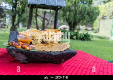 Typisch salvadorianisches Gericht, Käse-Pupusas mit Kohl und Tomatensauce. Reis- und Maispupusas gefüllt mit Käse, Bohnen oder anderen Zutaten Stockfoto