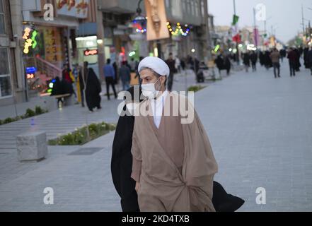 Ein iranischer Geistlicher und seine verschleierte junge Tochter, die Schutzmasken trägt, gehen am 10. März 2022 in der heiligen Stadt Qom 145km (90 Meilen) südlich von Teheran entlang einer Straße in der Nähe eines Schreins. (Foto von Morteza Nikoubazl/NurPhoto) Stockfoto