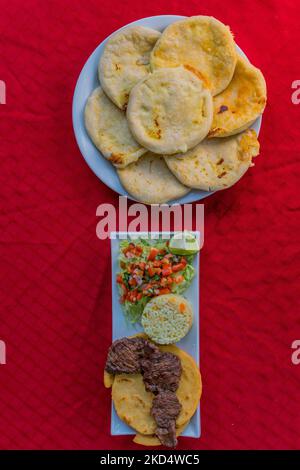 Typisch salvadorianisches Gericht, Käse-Pupusas mit Kohl und Tomatensauce. Reis- und Maispupusas gefüllt mit Käse, Bohnen oder anderen Zutaten Stockfoto