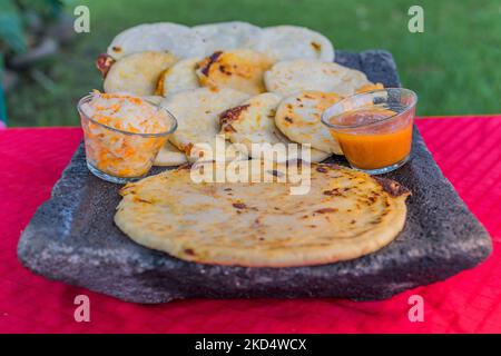 Typisch salvadorianisches Gericht, Käse-Pupusas mit Kohl und Tomatensauce. Reis- und Maispupusas gefüllt mit Käse, Bohnen oder anderen Zutaten Stockfoto