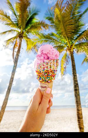 Eis und Palmen Hollywood Beach, am frühen Morgen Hand halten Erdbeer Eis mit Kegel am Strand, Miami, South Florida, USA Stockfoto