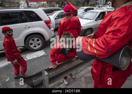 Ein junger Iraner malte sein Gesicht in Schwarz und trug rote Kleider, wie Hajji Firuz (ein iranisches Neujahrssymbol) am 12. März 2022 auf einer Straße im Norden Teherans steht. Hajji Firuz ist eine fiktive Figur in der iranischen Folklore, die zu Beginn von Nowruz auf den Straßen auftaucht. Sein Gesicht ist mit Ruß bedeckt, und er ist in leuchtend rote Kleider gekleidet. Er tanzt durch die Straßen, singt und spielt Musik. (Foto von Morteza Nikoubazl/NurPhoto) Stockfoto