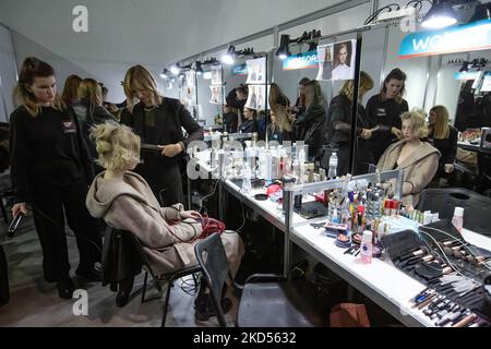 Makeup-Künstler stylen die Haare eines Models im Hintergrund während der Ukrainischen Fashion Week Herbst-Winter 2022-23 in Kiew. Die Ukrainian Fashion Week wurde 1997 gegründet und wurde die erste Pret-a-Porter Week in Osteuropa. Stockfoto