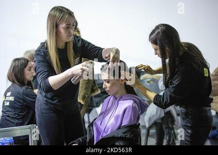 Makeup-Künstler stylen die Haare eines Models im Hintergrund während der Ukrainischen Fashion Week Herbst-Winter 2022-23 in Kiew. Die Ukrainian Fashion Week wurde 1997 gegründet und wurde die erste Pret-a-Porter Week in Osteuropa. Stockfoto