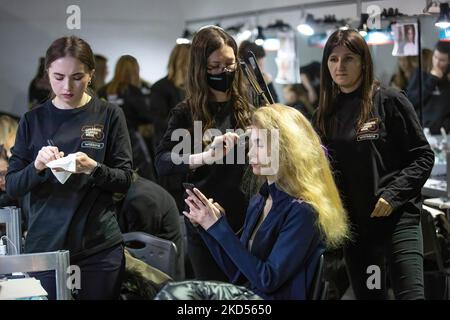 Makeup-Künstler stylen die Haare eines Models im Hintergrund während der Ukrainischen Fashion Week Herbst-Winter 2022-23 in Kiew. Die Ukrainian Fashion Week wurde 1997 gegründet und wurde die erste Pret-a-Porter Week in Osteuropa. Stockfoto