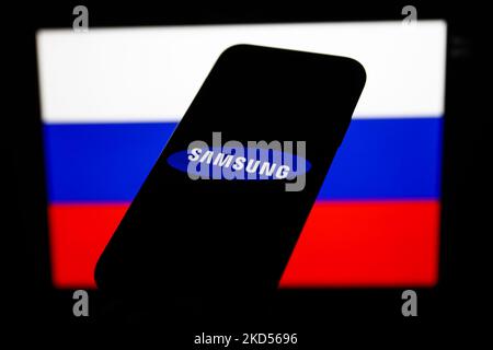 Das Samsung-Logo auf einem Telefonbildschirm und die russische Flagge auf einem Bildschirm im Hintergrund sind auf diesem Illustrationsfoto zu sehen, das am 14. März 2022 in Krakau, Polen, aufgenommen wurde (Fotollustration von Jakub Porzycki/NurPhoto) Stockfoto