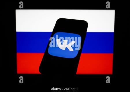 Das Logo von V Kontakte auf einem Telefonbildschirm und die russische Flagge auf einem Bildschirm im Hintergrund sind auf diesem Bild zu sehen, das am 14. März 2022 in Krakau, Polen, aufgenommen wurde (Fotollustration von Jakub Porzycki/NurPhoto) Stockfoto