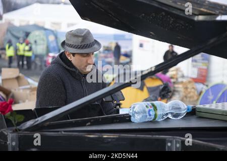Davide Martello, der deutsche Pianist italienischer Abstammung, bekannt als Klavierkunst, spielt in Medyka, am ukrainischen polnischen Grenzübergang von Medyka Shehyni. Der Musiker, ein Künstler, spielt in der Nähe der ukrainischen Grenze für die ankommenden Kriegsflüchtlinge aus der Ukraine vor den Zelten und Bussen, die sie zur Umsiedlung bringen. Tausende von zivilen Flüchtlingen überqueren aufgrund der russischen Invasion in die Ukraine täglich die ukrainisch-polnische Grenze. Medyka, Polen am 14. März 2022 (Foto von Nicolas Economou/NurPhoto) Stockfoto