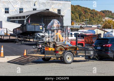 GALAX, VIRGINIA, USA-15 OCTOBER 2022: Mann entfernt den fahrenden Rasenmäher vom Anhänger, während Frau zuschaut. Stockfoto