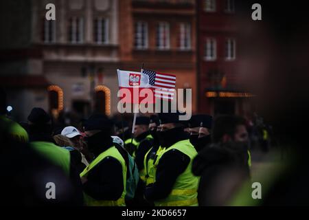 Polnische und amerikanische Flaggen sind am 26. März 2022 in Warschau, Polen, zwischen einem Polizeikordon in der Nähe des Königsschlosses zu sehen. Präsident Biden besuchte am Samstag gemeinsam mit Rafal Trzaskowski, dem Bürgermeister von Warschau und dem polnischen Premierminister Mateusz Morawiecki Flüchtlinge aus der Ukraine im Nationalstadion in Warschau. Präsident Biden hielt auch eine feurige Rede gegen die russische Invasion in der Ukraine und versicherte, dass die NATO alle ihre Mitgliedsstaaten um jeden Preis gegen jede Aggression verteidigen wird. (Foto von STR/NurPhoto) Stockfoto