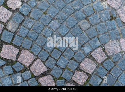 Zweifarbige gepflasterte Granitsteine der Gehstraße. Blick von oben Stockfoto