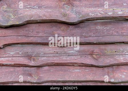 Zaun aus rohen alten Holzbrettern mit abblätternder dunkelbrauner Farbe. Horizontale Anordnung Stockfoto