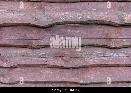 Zaun aus rohen alten Holzbrettern mit abblätternder dunkelbrauner Farbe. Horizontale Anordnung Stockfoto