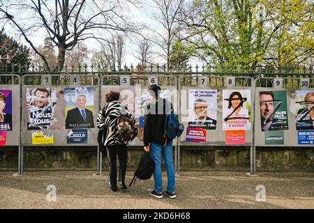 Menschen, die am 31. März 2022 in Clermont-Ferrand, Frankreich, auf die zerstörten Plakate der französischen Präsidentschaftskandidaten schauen. (Foto von Adrien Fillon/NurPhoto) Stockfoto