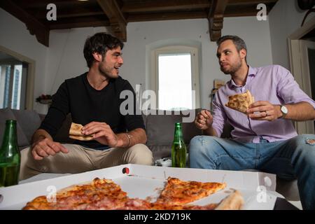 Zwei männliche Freunde verbringen zu Hause Zeit mit Pizza und Bier. Stockfoto