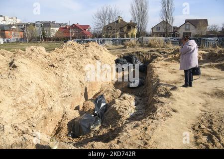 (ANMERKUNG DER REDAKTION: Grafischer Inhalt) die Frau steht in der Nähe des Massengrabes von Zivilisten, die von der russischen Armee getötet wurden, in der Stadt Bucha, die von der ukrainischen Armee erobert wurde, im Raum Kiew, Ukraine, 07. April 2022 (Foto: Maxym Marusenko/NurPhoto) Stockfoto