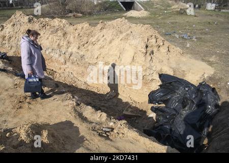 (ANMERKUNG DER REDAKTION: Grafischer Inhalt) die Frau steht in der Nähe des Massengrabes von Zivilisten, die von der russischen Armee getötet wurden, in der Stadt Bucha, die von der ukrainischen Armee erobert wurde, im Raum Kiew, Ukraine, 07. April 2022 (Foto: Maxym Marusenko/NurPhoto) Stockfoto