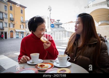 Chinesische Freundinnen unterhalten sich beim Cappuccino- und Gebäckfrühstück im Café, chinesische Freundinnen unterhalten sich beim Cappuccino und Gebäck Stockfoto
