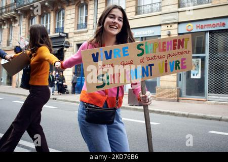 Eine junge Frau reagiert während des Laufs der Menschenkette. Sie hält ein Plakat mit der Aufschrift „Leben einfach für andere, um einfach zu leben“. Am Tag vor der ersten Runde der französischen Präsidentschaftswahlen riefen Hunderte von Kollektiven in ganz Frankreich dazu auf, „in die Zukunft zu blicken“, um die Kandidaten für die Präsidentschaft in all den Krisenzeiten zurückzurufen: Klima, Biodiversität, Kriege, wachsende Ungleichheit, Gesundheit, Aussterben von Arten usw. in Toulouse riefen mehr als 30 Organisationen zum "Marsch für die Zukunft" (NousToutes, XR, YFC, Greenpeace...) auf und um eine Menschenkette zu bilden. Mehrere Tausend Menschen kamen an Stockfoto