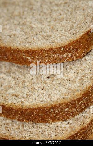 Makro-Nahaufnahme von Scheiben Vollkornbrot, versetzt voneinander - Konzept für gesunde Lebensmittel, gesunde Ernährung, Brotscheiben, Morgenrösten, Stockfoto