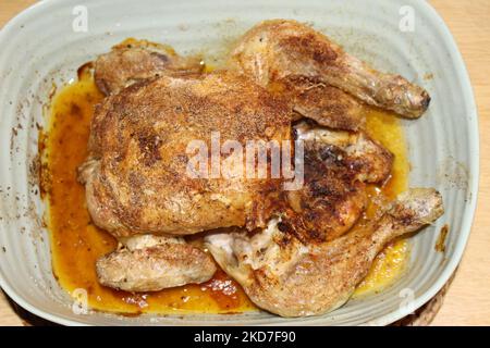 Draufsicht auf ganze gebratene Hähnchen in hellblauer Keramikschale. Hausgemachte gewürzte und gekochte ganze gebratene Hähnchen in einem Tablett. Makro-Nahaufnahme Stockfoto