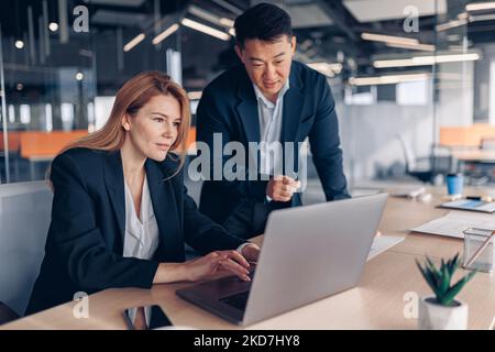 Zwei multiethnische Mitarbeiter arbeiten zusammen und analysieren die Charts im Büro Stockfoto