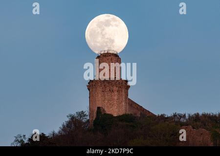 Am 15. April 2022 erhebt sich hinter einem Turm in Assisi, Umbrien, Italien, der vollrosa Mond. (Foto von Lorenzo Di Cola/NurPhoto) Stockfoto