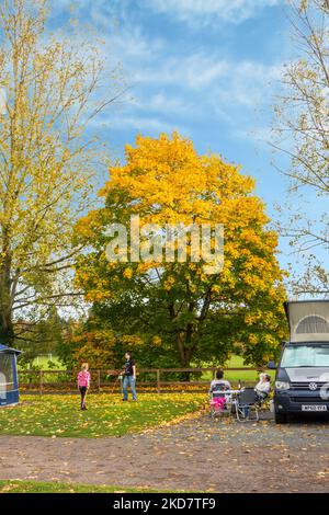 Familie, die die Herbstsonne genießt und draußen Spiele spielt, während sie in ihrem Wohnmobil auf dem Wolverley Camping and Caravan Club-Gelände in Worcestershire zeltet Stockfoto