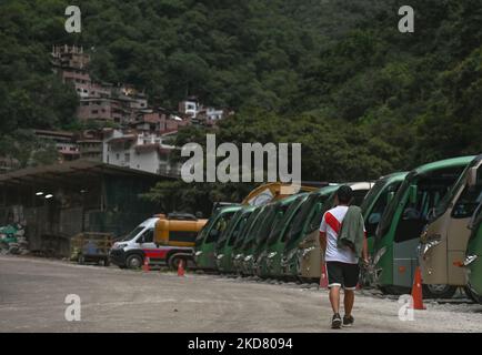 Ein Mann in einem peruanischen Fußballtrikot geht an einer Buslinie in Aguas Calientes vorbei. Gewerkschaftsführer der Region Cusco starteten heute Morgen einen 48-stündigen Streik, um gegen die steigenden Preise für Nahrungsmittel, Kraftstoff und Düngemittel zu protestieren und die Regierung um Hilfe bei der Überwindung der Krise zu bitten. Der Streik in Cusco blockierte den Straßen- und Bahnzugang zu den Ruinen von Machu Picchu, der wichtigsten Touristenattraktion des Landes, und Zufahrtsstraßen nach Cusco, der Hauptstadt der Region, wo Tausende unschuldiger Touristen einsperrten. Am Montag, den 18. April 2022, in Aguas Calientes, Cusco, Peru. (Foto von Artur Widak/NurPhoto) Stockfoto