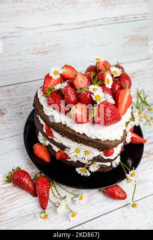 Schokoladen-Erdbeer-Herzkuchen mit Kamillenblumen-Dekoration Stockfoto