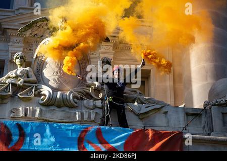 Ein Demonstrator mit dem Aussterben Rebellion DC winkt Rauchmelder, nachdem er das John A. Wilson-Gebäude erklimmen und am 22. April 2022 in Washington, D.C. ein Banner gegen die Praktiken von Washington Gas entrollt hat (Foto: Bryan Olin Dozier/NurPhoto) Stockfoto