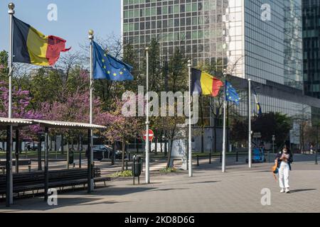 Die Menschen gehen vor den Fahnenmasten mit wehenden Flaggen Belgiens und der EU. Die Flagge Europas winkt an einem sonnigen Tag unter den hohen Gebäuden der europäischen Hauptstadt Brüssel in der Nähe des Brüsseler Nordbahnhofs am blauen Himmel. Die Europaflagge oder die Europaflagge ist das Symbol des Europarat CoE und der EU der Europäischen Union, wie sie in der belgischen Hauptstadt Brussel zu sehen ist. Brüssel, Belgien am 24. April 2022 (Foto von Nicolas Economou/NurPhoto) Stockfoto