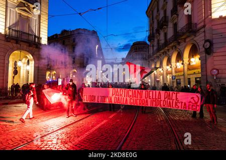 Ein Protestler hält eine rote Rauchbombe in der Hand, um die PD-Fahne (Demokratische Partei) zu verbrennen, um gegen die Beteiligung der italienischen Regierung an der ukrainischen Krise zu protestieren. Nach der Pause aufgrund von Zwangsbeschränkungen kehrt am 24. April 2022 der traditionelle Fackelzug zum Jahrestag der Befreiung in Turin, Italien, zurück. Der Jahrestag der Befreiung Italiens ist ein Feiertag, der jedes Jahr in Italien begangen wird, um dem Ende der Nazi-Besatzung des Landes und dem Zusammenbruch des faschistischen Regimes zu gedenken. (Foto von Mauro Ujetto/NurPhoto) Stockfoto