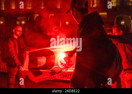 Ein Protestler hält eine rote Rauchbombe in der Hand, um die PD-Fahne (Demokratische Partei) zu verbrennen, um gegen die Beteiligung der italienischen Regierung an der ukrainischen Krise zu protestieren. Nach der Pause aufgrund von Zwangsbeschränkungen kehrt am 24. April 2022 der traditionelle Fackelzug zum Jahrestag der Befreiung in Turin, Italien, zurück. Der Jahrestag der Befreiung Italiens ist ein Feiertag, der jedes Jahr in Italien begangen wird, um dem Ende der Nazi-Besatzung des Landes und dem Zusammenbruch des faschistischen Regimes zu gedenken. (Foto von Mauro Ujetto/NurPhoto) Stockfoto
