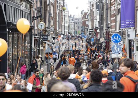 Die Niederlande feiern den Königstag nach zwei Jahren der Annullierung aufgrund der COVID-19 Coronavirus-Pandemie und der Sperrbeschränkungen und -Maßnahmen. Tausende von Einheimischen, Feiernden und Besuchern haben das Stadtzentrum, die Parks in der Nähe des Rijksmuseums, die Grachten von Amsterdam besucht, um mit verschiedenen Festlichkeiten den Geburtstag von König Willem-Alexander zu feiern, der als Koningsdag bekannt ist, ein niederländischer Nationalfeiertag. Alle Arten von Booten und Schiffen werden in den Kanälen gesehen, die unter den berühmten Brücken und in der Nähe der engen Häuser von Amsterdam vorbeifahren, mit Leuten, die tanzen und Spaß haben. Die Boote ziehen in der innen nach unten Stockfoto