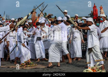 Balinesische Hindu-Anhänger treten mit traditionellen Dolchen namens Keris während der Melasti auf, einer Reinigungszeremonie vor Nyepi am Padang Galak Strand in Denpasar, Bali, Indonesien, 28. Februar 2022. Das Melasti-Ritual findet jährlich vor dem Nyepi-Tag der Stille statt, einer Zeremonie, die die Seelen der balinesischen Hindu-Teilnehmer reinigen und reinigen soll. Nyepi ist eine hinduistische Feier, die jedes neue Jahr nach dem balinesischen Kalender gefeiert wird. Der Nationalfeiertag ist ein Feiertag der Selbstreflexion und Meditation und Aktivitäten wie Arbeiten, Fernsehen schauen, oder Reisen ist zwischen t beschränkt Stockfoto