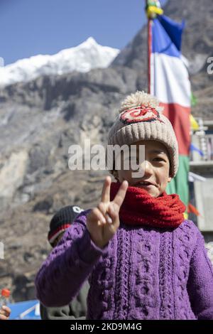 Schüler, Schüler, wie sie außerhalb der örtlichen Schule unter dem Langtang Lirung Peak gesehen werden. Langtang Lirung Peak aus Sicht des Dorfes Langtang, Teil des Langtang Himal Berges in Nepal mit dem höchsten Punkt in einer Höhe von 7234m oder 23734 Fuß. Der Langtang Lirung ist der 99. höchste Berg der Welt und wurde 1978 zum ersten Mal erreicht. Am 25. April 2015 führte ein massives Erdbeben der Stärke 7,8 zu einer Lawine und einem Erdrutsch im Dorf Langtang, bei dem direkt 243 Menschen getötet und das Dorf verschwungen wurden. Der Langtang National Park ist ein beliebtes Trekking- und Reiseland für Fore Stockfoto