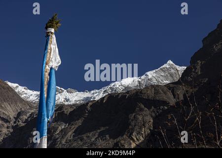 Tibetisch - buddhistische religiöse Gebetsfahne zusammen mit dem Langtang Lirung Gipfel. Langtang Lirung Peak aus Sicht des Dorfes Langtang, Teil des Langtang Himal Berges in Nepal mit dem höchsten Punkt in einer Höhe von 7234m oder 23734 Fuß. Der Langtang Lirung ist der 99. höchste Berg der Welt und wurde 1978 zum ersten Mal erreicht. Am 25. April 2015 führte ein massives Erdbeben der Stärke 7,8 zu einer Lawine und einem Erdrutsch im Dorf Langtang, bei dem direkt 243 Menschen getötet und das Dorf verschwungen wurden. Der Langtang National Park ist ein beliebtes Trekking- und Reiseland für ausländische Wanderer Stockfoto