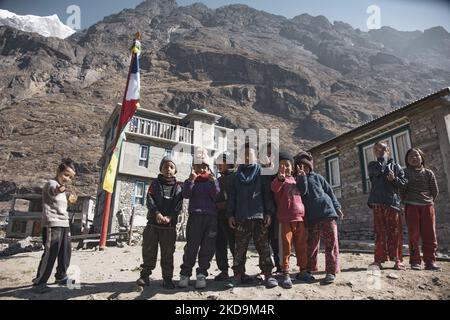 Schüler, Schüler, wie sie außerhalb der örtlichen Schule unter dem Langtang Lirung Peak gesehen werden. Langtang Lirung Peak aus Sicht des Dorfes Langtang, Teil des Langtang Himal Berges in Nepal mit dem höchsten Punkt in einer Höhe von 7234m oder 23734 Fuß. Der Langtang Lirung ist der 99. höchste Berg der Welt und wurde 1978 zum ersten Mal erreicht. Am 25. April 2015 führte ein massives Erdbeben der Stärke 7,8 zu einer Lawine und einem Erdrutsch im Dorf Langtang, bei dem direkt 243 Menschen getötet und das Dorf verschwungen wurden. Der Langtang National Park ist ein beliebtes Trekking- und Reiseland für Fore Stockfoto